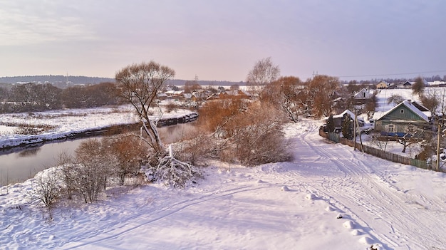 Zdjęcie zimowy krajobraz rzeczny pokryte śniegiem pola szron na drzewach rośliny mroźny wieczór słoneczny pochmurny mglista pogoda zimna pora roku spokojna przyroda wieś