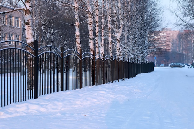 Zimowy krajobraz żelazne ogrodzenie o zachodzie słońca