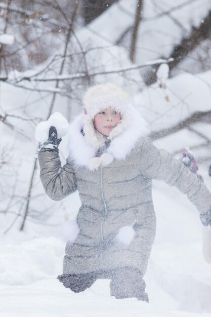 Zimowy las mała dziewczynka grozi śnieżkami śnieżnymi