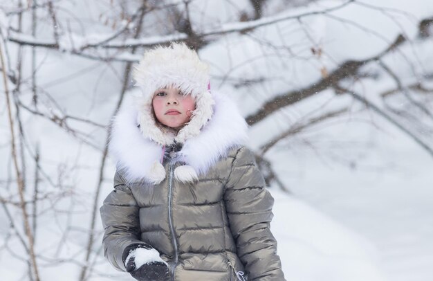 Zimowy las mała dziewczynka wygląda na zdenerwowaną złociła śnieżkę
