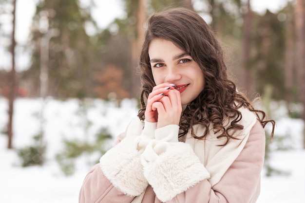 Zimowy portret wesołej kobiety brunetka nosi szalik i ciepły płaszcz spaceru w lesie. Pusta przestrzeń