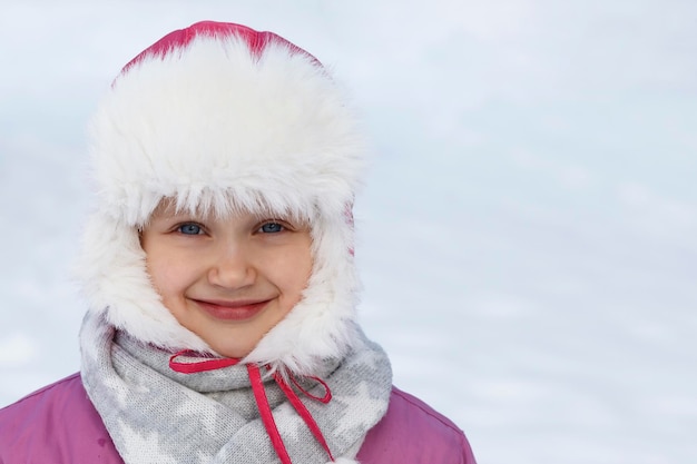 Zimowy portret z bliska Zimowe wakacje Zimowe ciepłe ubrania Dziecko dziewczynka w ciepłym futrzanym kapeluszu w śniegu