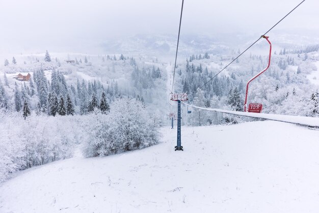 Zimowy widok na śnieżny las sosnowy i kolejkę narciarską w górach