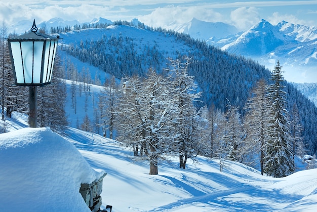 Zimowy zamglony widok z masywu górskiego Dachstein (Austria) i lampa przy wejściu do hotelu