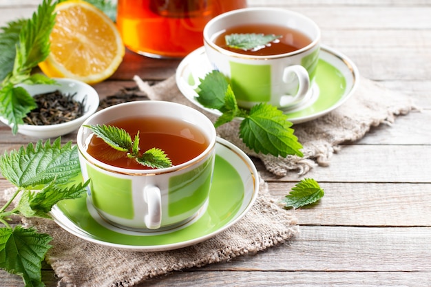 Ziołowa herbata pokrzywowa w dwóch filiżankach na drewnianym stole