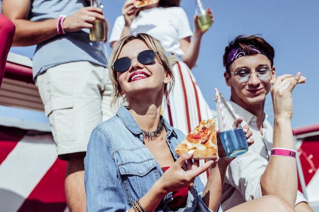 Zjedz to. Wesoły chłopiec je pizzę, patrząc na bok