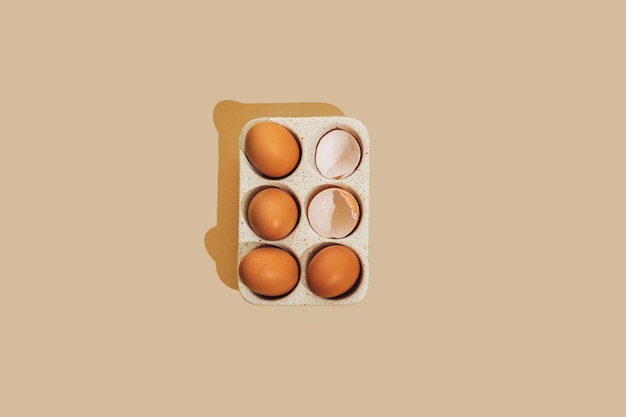 Złamane brązowe surowe jajko kurze ze skorupką jajka w ceramicznej tacy do przechowywania na beżowym tle z miejscem na kopię Kreatywny świąteczny wystrój wielkanocny lub świąteczny i wiosenna kartka z życzeniami Płaska świecka