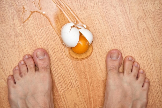 Złamane jajko i stopy na podłodze w kuchni