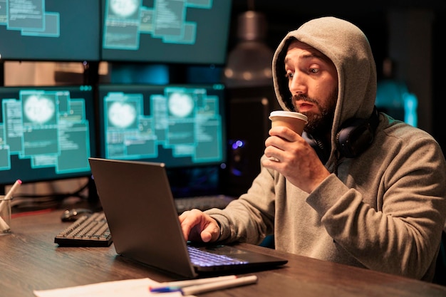 Złodziej programowania IT włamuje się do systemu komputerowego w biurze, pije filiżankę kawy i zachowuje się niebezpiecznie. Kradzież informacji z oprogramowania do dużych zbiorów danych, łamanie serwera bezpieczeństwa wirusem i kodem.