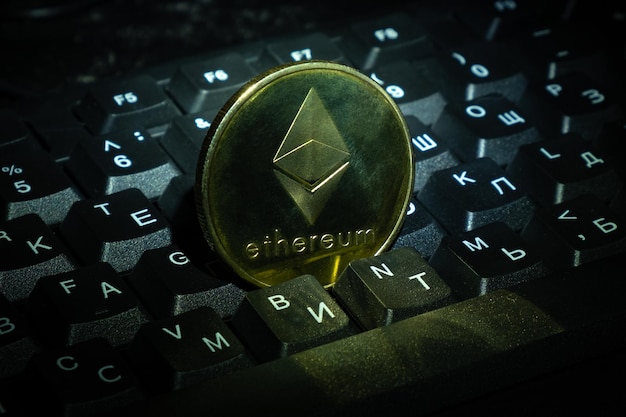 Złota moneta Ethereum (ETH) na klawiaturze z bliska zakupy kryptowalut i zarabianie pieniędzy w Internecie.