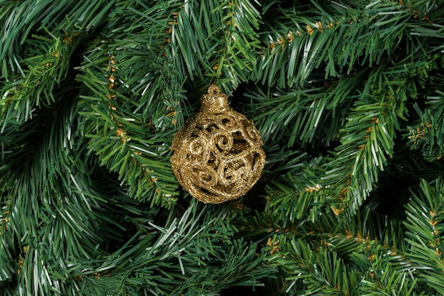 Złota piłka Boże Narodzenie na białym tle na gałęzi choinki.