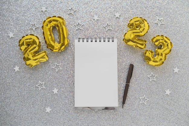 złote balony foliowe i notatnik z długopisem na tle bożego narodzenia
