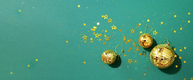 Zdjęcie złote bombki z błyszczącymi gwiazdami na zielonym tle