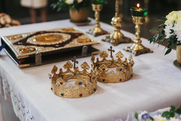 Złote korony i biblia na świętym ołtarzu podczas ceremonii ślubnej w kościelnych duchowych chwilach świętego małżeństwa