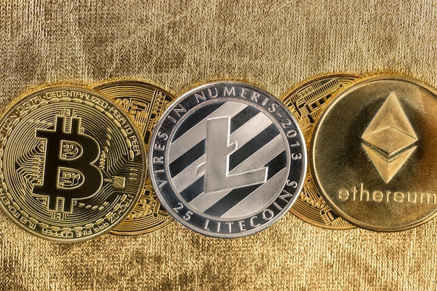 Złote monety kryptowaluty - Bitcoin, Ethereum, Litecoin na tle bryłek złota. Koncepcja wirtualnych pieniędzy.