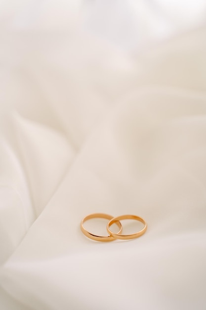 złote obrączki ślubne leżą na białym welonie lub tiulu bez miejsca na tekst
