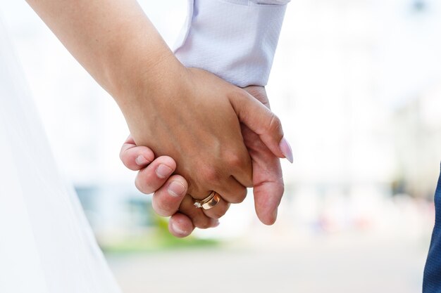 Złote obrączki ślubne w rękach nowożeńców