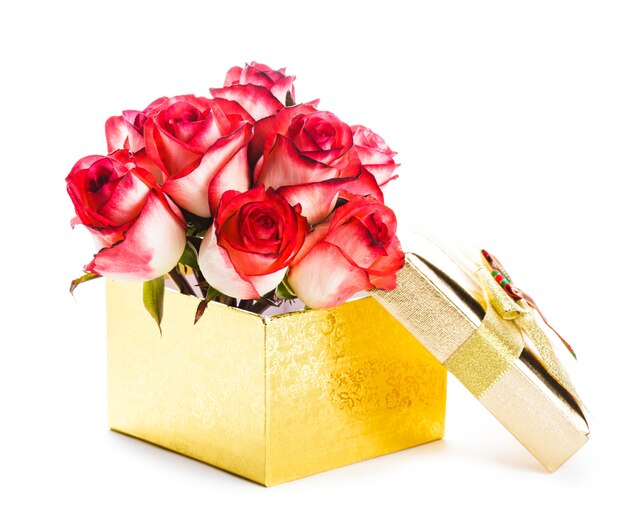 Złote pudełko i bukiet róż na białym tle