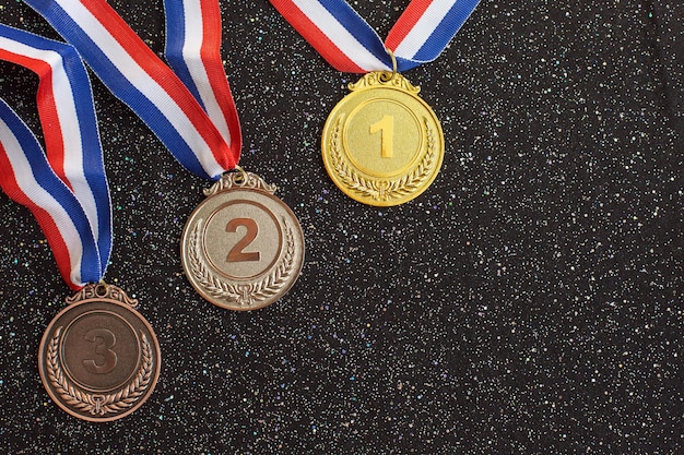 Złote, srebrne i brązowe medale z numerami jeden dwa trzy i wstęgi