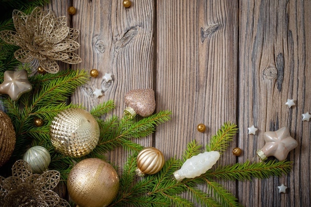 Złote świąteczne zabawki z gałęziami jodły na ciemnym drewnianym tle