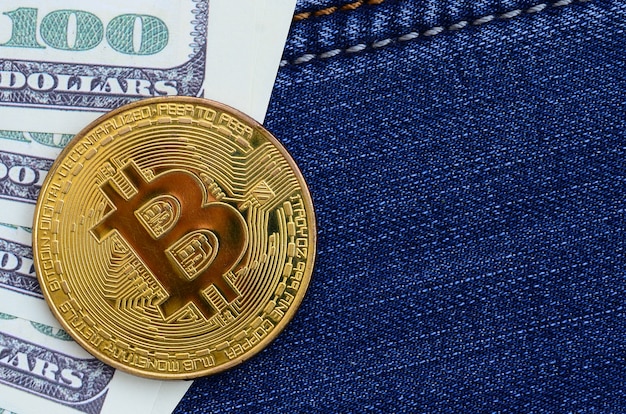 Złoty Bitcoin I Banknotów Dolarowych Leży Na Tkaninie Blue Jeans. Nowe Wirtualne Pieniądze. Nowa Kryptowaluta W Postaci Monet