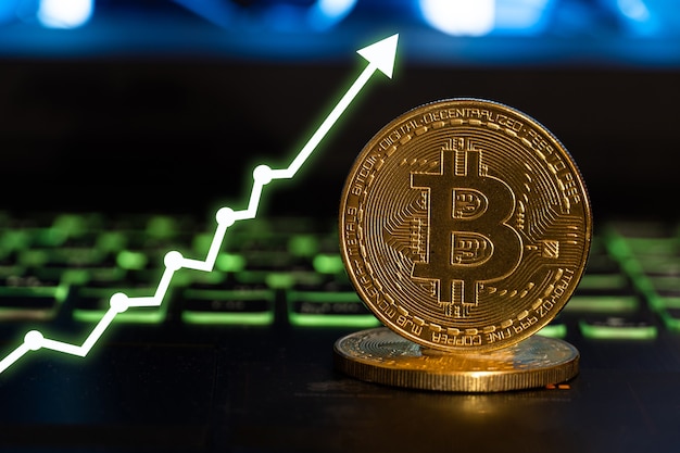 Złoty bitcoin z wykresami rosnącą strzałką.