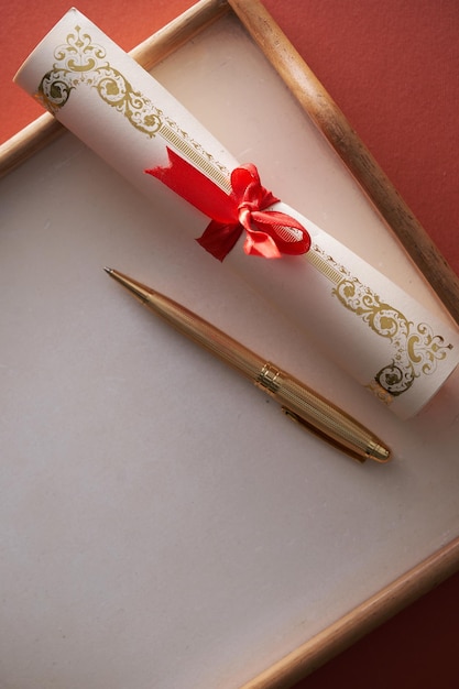 Złoty długopis i zwój certyfikatu ze wstążką
