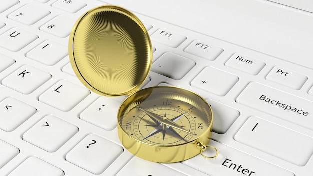 Złoty kompas na białej klawiaturze laptopa