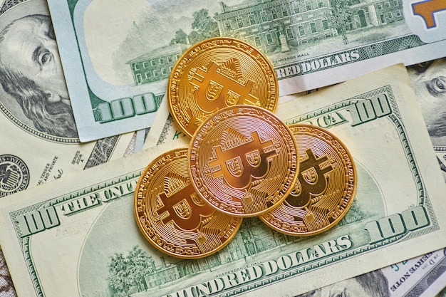 Złoty metalowy bitcoin na tle dolara