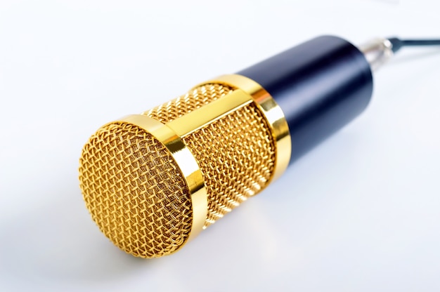 Zdjęcie złoty mikrofon na białej powierzchni. motyw muzyczny. mikrofon pojemnościowy. ścieśniać