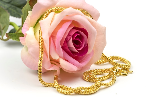 złoty naszyjnik z różową różą na białej powierzchni