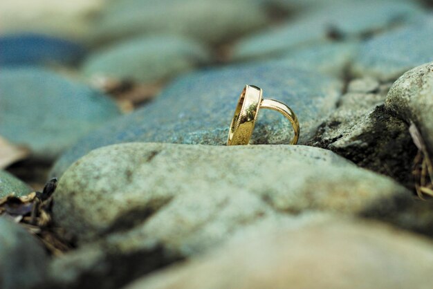 Złoty pierścionek siedzi na skale w piasku.