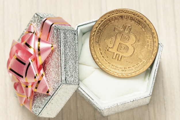 Zdjęcie złoty wirtualny bitcoin na monety i pudełko z różową wstążką