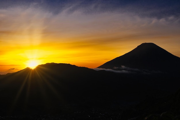 Złoty wschód słońca zza gór Sindoro i Sumbing w środkowej Jawie w Indonezji