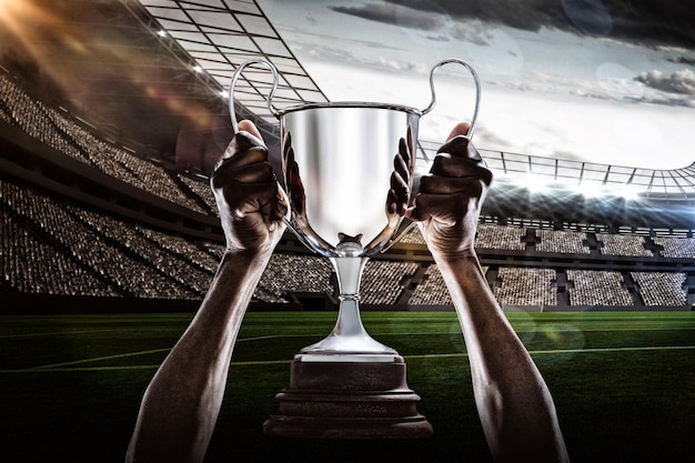Złożony obraz 3D przyciętej ręki sportowca trzymającego trofeum