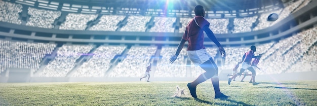 Złożony obraz gracza rugby kopiącego piłkę do kolegów z drużyny na boisku