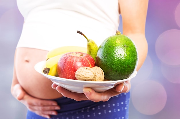 Złożony obraz kobiety w ciąży przedstawiający owoce i warzywa