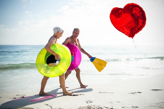 Złożony obraz starszej pary na plaży i balon z czerwonym sercem 3d