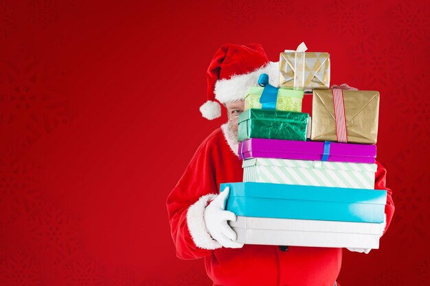 Złożony obraz Świętego Mikołaja chowającego się za prezentami świątecznymi