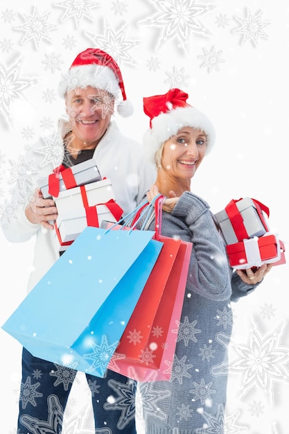 Złożony wizerunek świąteczna dojrzała para w zimie odziewa trzyma prezenty i torby