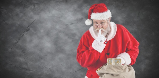 Złożony wizerunek Świętego Mikołaja z palcem na ustach i trzymającego prezent
