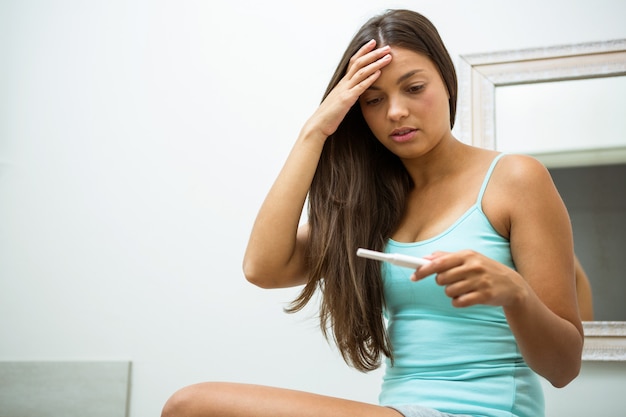 Zmartwiona kobieta patrzeje test ciążowy