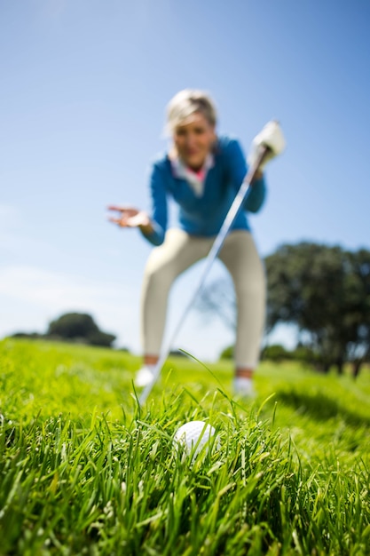 Zdjęcie zmartwiony żeński golfista patrzeje piłkę golfową