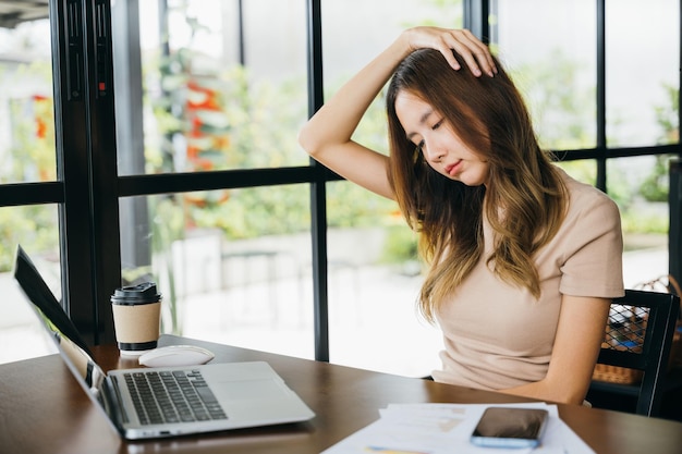 Zmęczona biurowa kobieta siedzi przy biurku dotykając masując sztywną szyję trzymając głowę w kawiarni