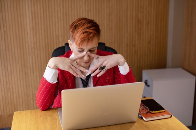 Zdjęcie zmęczona bizneswoman w stresie pracuje przy laptopie ból głowy