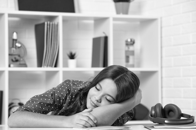 Zmęczona i znudzona nastolatka uczennica Uczennica śpi podczas odrabiania lekcji zmęczona nauką wyczerpana
