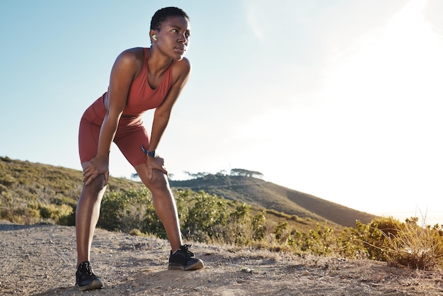 Zmęczona pocenie się i oddychanie czarnej kobiety fitness i trening celują w zmęczenie ciała i silne nastawienie w górach z makietą Lekkoatletka robi sobie przerwę, aby odetchnąć od treningu sportowego w przyrodzie