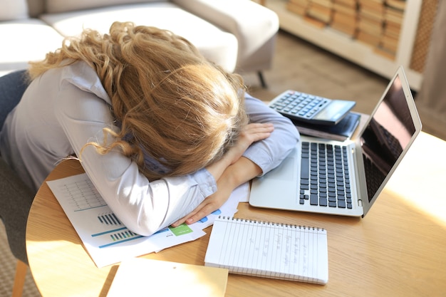 Zdjęcie zmęczona, przepracowana kobieta odpoczywa podczas pracy na laptopie.