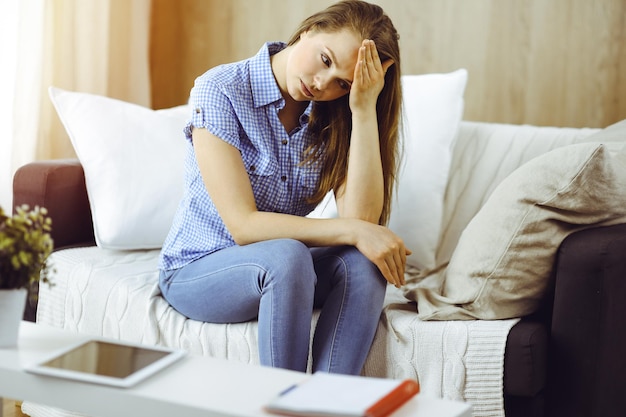 Zmęczona zdenerwowana kobieta martwi się zmęczeniem pracą domową i kwarantanną samoizolacji z powodu koronawirusa COVID-19.