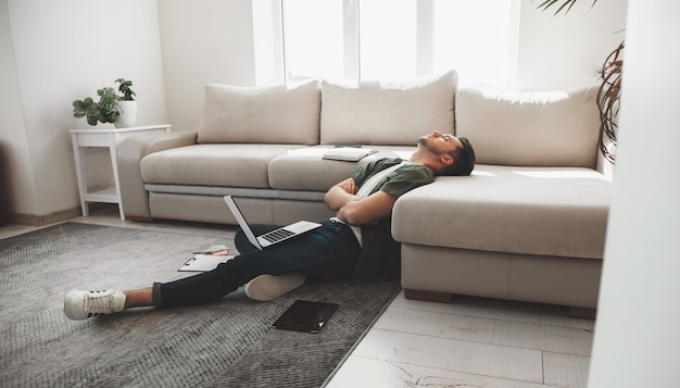 Zmęczony Kaukaski Mężczyzna Zasypia Na Podłodze Z Komputerem I Tabletem Ze Skrzyżowanymi Rękami